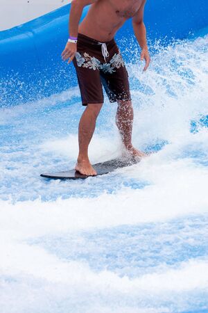 A surfer in brown shorts in a blue wave poolの写真素材