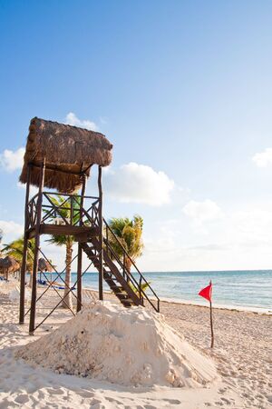 A wood lifeguard station on a beach with a warning flag in the windの写真素材