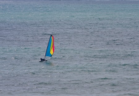 A colorful sailboat tacking on stormy blue waterの写真素材