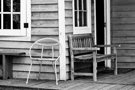 A bright yellow metal chair on the porch of an old bungalowの写真素材