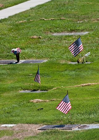 Three American Flags by graves in a cemeteryの写真素材