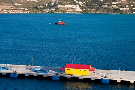 A red tugboat in blue water by red and yellow buildingの写真素材