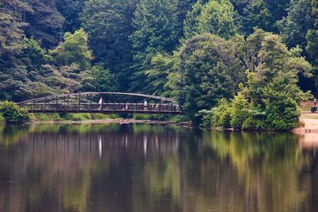 A rusty metal bridge over a lake in a parkの写真素材