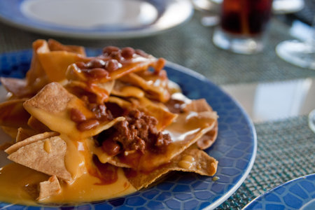 A plate of nachos with chili and cheese on a blue plateの写真素材