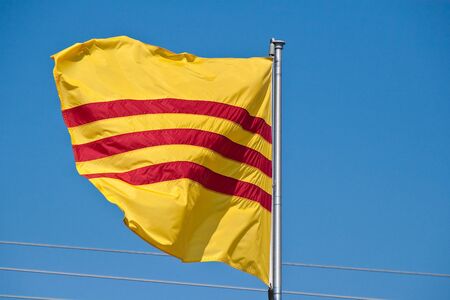 Yellow and Red Vietnamese flag blowing against a blue skyの写真素材