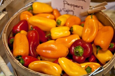 A bucket of fresh peppers for sale at a marketの写真素材