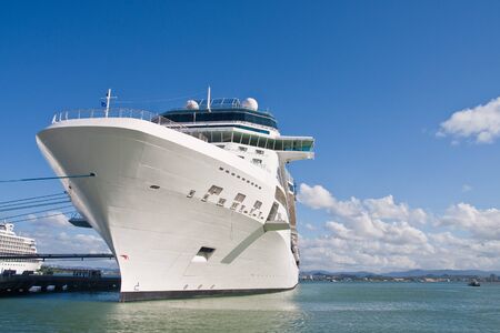 A white luxury cruise ship tied to a pier under blue skies on calm waterの写真素材