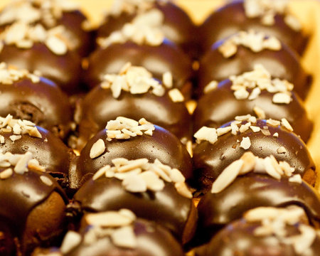 Chocolate covered pastries or candies with nut topping
