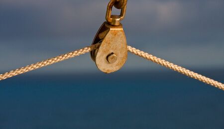 An old rusty pulley with a rope against blue backgroundの写真素材