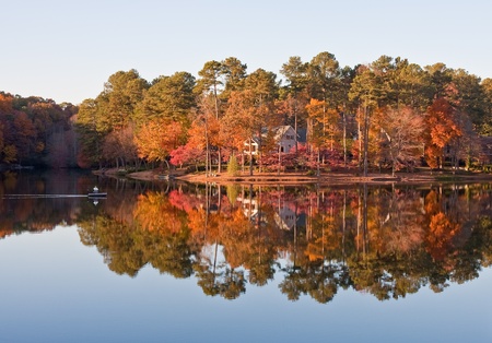 A man in a small boat on a calm lake in autumnの写真素材