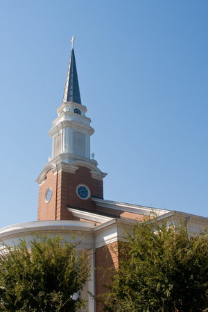 A modern brick church steeple rising out of trees