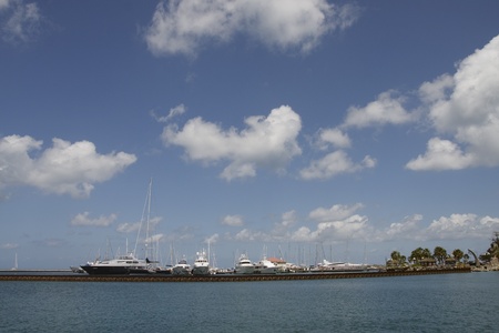 Luxury yachts and sailboats at a long pier under blue skiesの写真素材