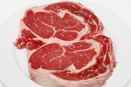 Two prime ribeye steaks on a white plateの写真素材