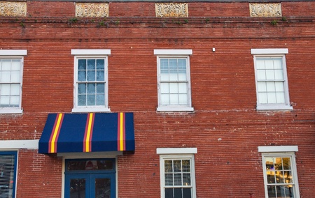 A blue, yellow and red awning over a blue door on an old brick warehouseの写真素材