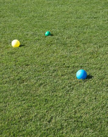 Blue, yellow and green bocce balls on green grass lawnの写真素材