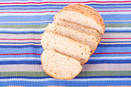 A loaf of whole grain bread sliced on a colorful placemaat