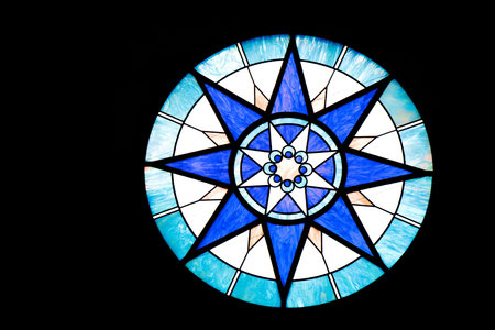 A round blue and white stained glass window on black background