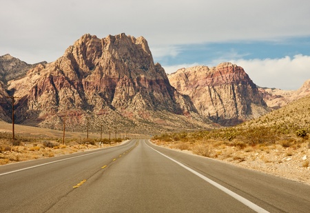 A wide empty road in the desert toward distant mountainsの写真素材