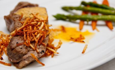 A grilled steak on a plate with grilled onions, asparagus and carrots with bernaise sauceの写真素材
