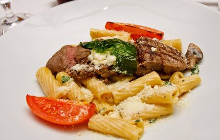 Beef ans pasta dish with tomatoes and mushrooms sprinkled with parmesan cheeseの写真素材