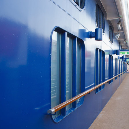 Blue hull with portholes and wood rail