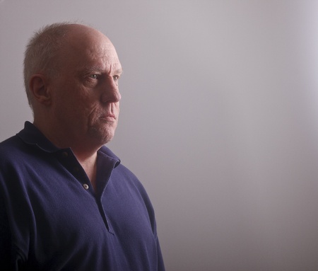 An older man in window light on a gray wallの写真素材