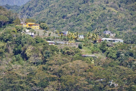 A bright yellow house on top of green tropical hillsideの写真素材