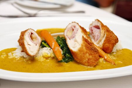 A gourmet dish of chicken cordon bleu with rice and sauceの写真素材