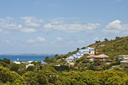 Homes on Tropical Hillside in Barbados with White Sailboat in Blue Bayの写真素材