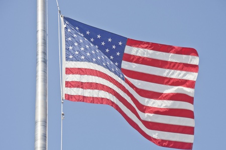 An American flag waving in the wind against a blue skyの写真素材