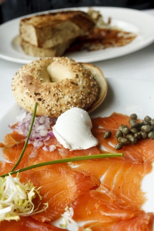 A platter of smoked salmon with a toasted everything bagel garnished with red onion, scallion, cream cheese and capersの写真素材