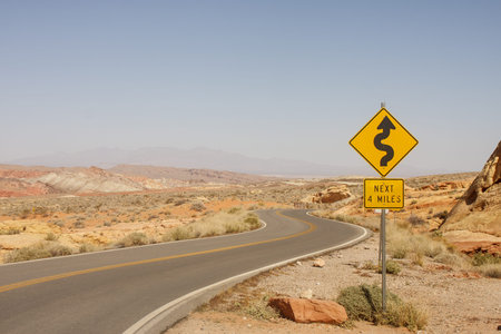 A road sign in the middle of a desert showing curves ahead