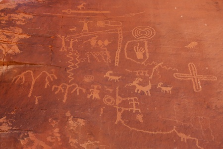 Indian carvings on a red rock wall in the desertの写真素材