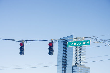 Two red lights on Lenox Road under clear blue skies