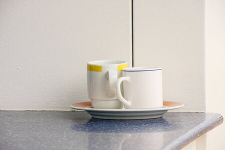 Two empty coffee cups on a saucer on blue counterの写真素材