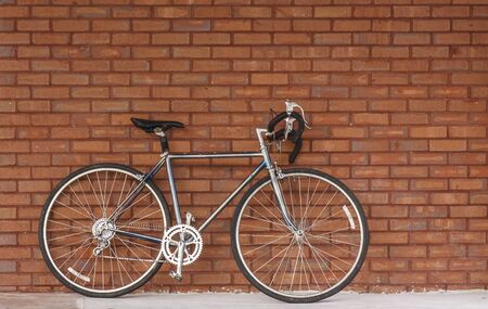 An old bicycle leaning against a red brick wallの写真素材