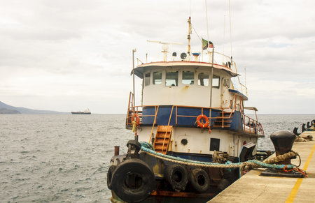 An old blue and white tugboat tied up at a pier