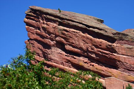 Red rock outcropping in trees under blue skyの写真素材