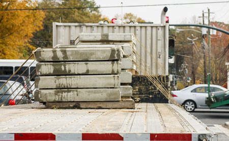 Precast units of concrete slab strapped to a flat bed truck on a busy streetの写真素材