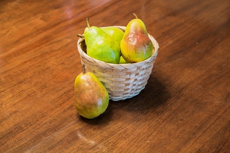 Fresh bartlett pears in a basket on a wood tableの写真素材