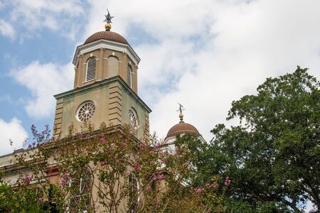 A classic church of brown stucco wtih domes steeples behind treesの写真素材