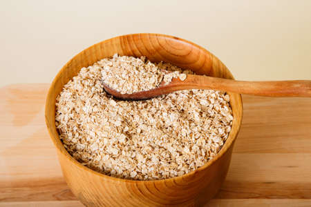 Fresh oats in a wood bowl with a wood spoonの写真素材