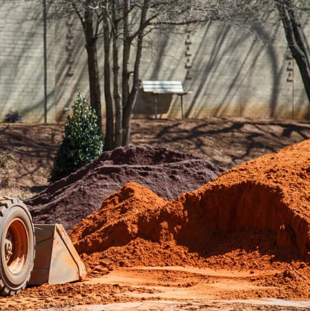 Small earth mover digging in pile of dirt at siteの写真素材