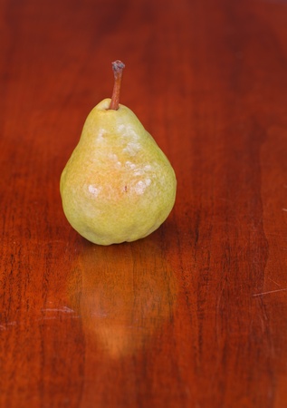 A single Bartlett or Williams pear on a wood table with slight reflectionの写真素材