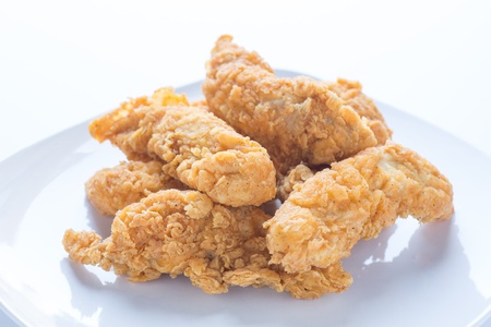 Fresh, fried chicken strips on a white plate in natural lightの写真素材
