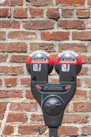 A pair of parking meters in front of a brick wallの写真素材