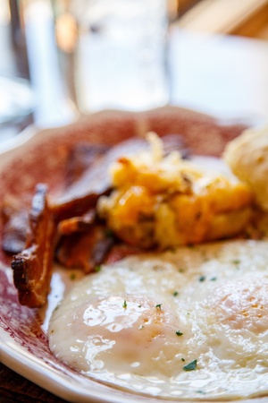 Hearty breakfast of fried eggs with bacon, potatoes and biscuitの写真素材