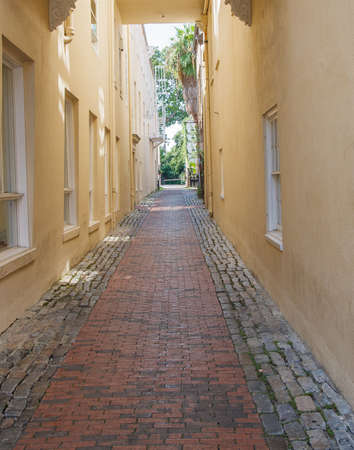 A narrow alley paved with bricks between yellow stucco wallsの写真素材
