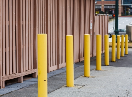 Yellow Metal posts descending into distance by brown wallの写真素材