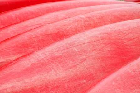 Bottoms of a line of Red Canoes with many scratches and dentsの写真素材